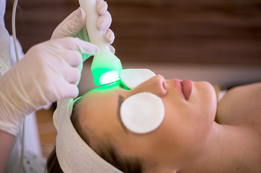 Woman at the spa getting a rejuvenation treatment on her face